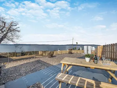 a picnic table on a patio with a view of the water at Postbox Cottage in Lochranza