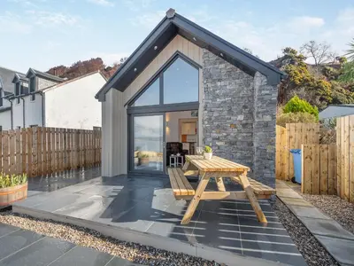 a small cottage with a picnic table in front of it at Postbox Cottage in Lochranza