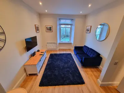 a living room with a blue couch and a television at The Rail & Ferry Den in Oban