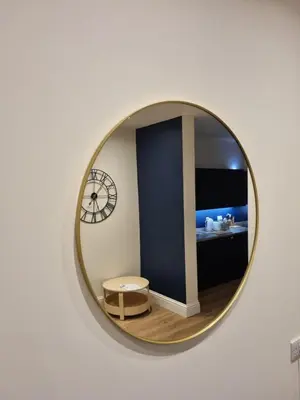 a round mirror on a wall with a table and a room at The Rail & Ferry Den in Oban