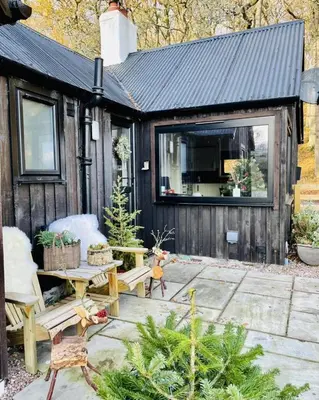 a cabin with a patio with a table and chairs at 2 bed lodge with private hot tub in Aviemore in Saint Ninians