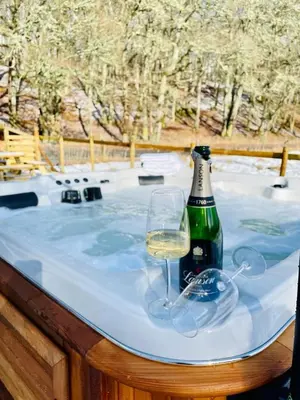 a bottle of wine and a glass on a hot tub at 2 bed lodge with private hot tub in Aviemore in Saint Ninians