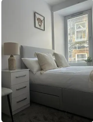 a white bedroom with a bed and a window at Combie Lane Apartments in Oban