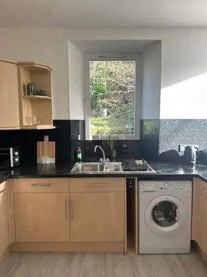 a kitchen with a sink and a washing machine at Combie Lane Apartments in Oban