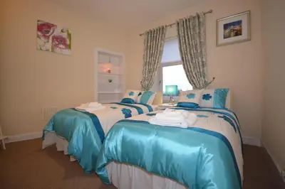 a bedroom with two beds with blue and white sheets at Wallace Apartment in Stirling
