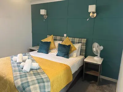 a bedroom with a bed with yellow and blue pillows at MacDonald Hotel & Cabins in Kinlochleven