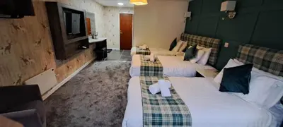 a room with three beds and a tv in it at MacDonald Hotel & Cabins in Kinlochleven
