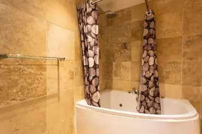 a bathroom with a shower curtain with logs on it at Argyll Barn in Colintraive