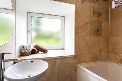 a bathroom with a sink and a window and a tub at Argyll Barn in Colintraive