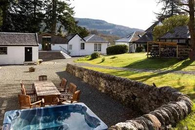 a hot tub in a yard with a table and chairs at Argyll Barn in Colintraive