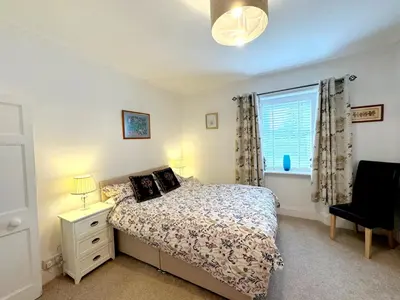 a bedroom with a bed and a window and a chair at Ameliafield Cottage, Prestwick in Prestwick