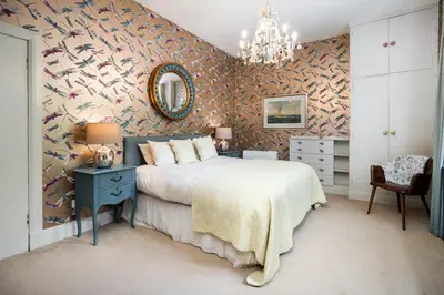 a bedroom with a bed and a wall covered in birds wallpaper at Loch View House in Kilfinan