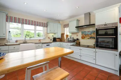 a kitchen with white cabinets and a wooden counter top at Seal Bay Cottage in Kilfinan