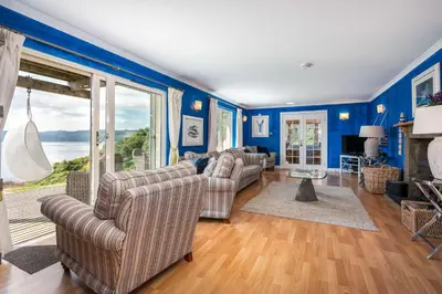 a living room with blue walls and couches at Seal Bay Cottage in Kilfinan