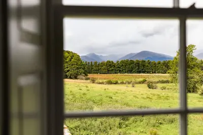 a view from a window of a field and mountains at Kilmaronock Manse B&B in Drymen