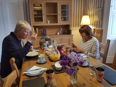 a man and woman sitting at a table eating food at Kilmaronock Manse B&B in Drymen
