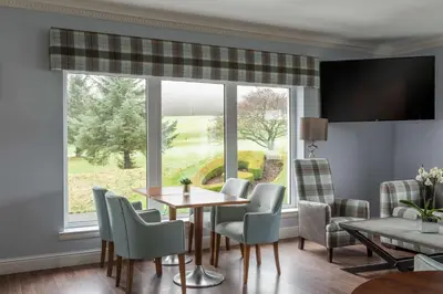 a dining room with a table and chairs and a large window at Gleddoch Golf & Spa Resort in Langbank