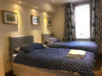 two beds in a bedroom with blue sheets and a window at Luxury Flat, 20 Minutes by train from Edinburgh in Inverkeithing