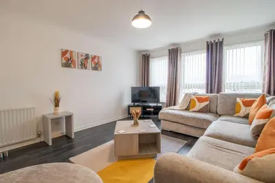 a living room with a couch and a tv at Park View-modern 2 bed apartment in Motherwell