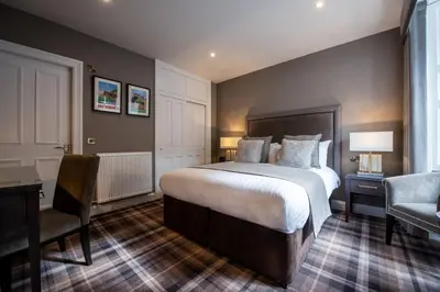 a bedroom with a bed and a desk and a chair at Royal Scots Club in Edinburgh