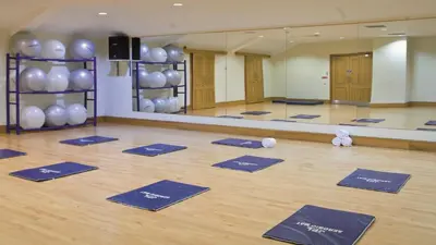 a yoga class with blue mats on a wooden floor at Macdonald Crutherland House in East Kilbride