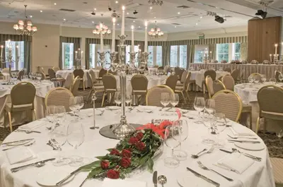 a banquet room with white tables with flowers and glasses at Macdonald Crutherland House in East Kilbride