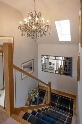 a living room with a chandelier and a staircase at Robin Cottage in Buchanty