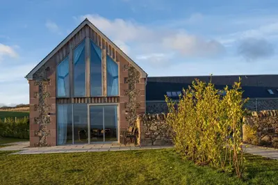 a house with glass windows and a stone wall at Robin Cottage in Buchanty