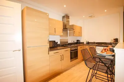 a kitchen with wooden cabinets and a table with chairs at City Hub by the Castle Free Designated Parking in Stirling