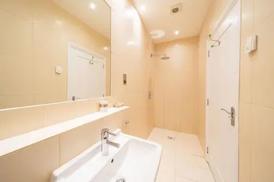 a white bathroom with a sink and a mirror at Lochelour Mill Cottage in Perth