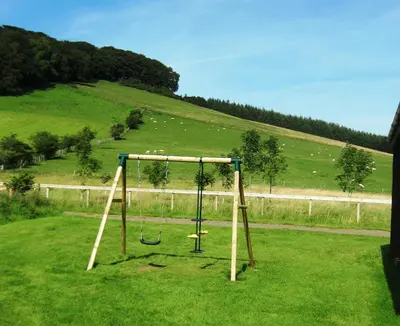 a swing set in a field with a hill at The New Farmhouse in Biggar