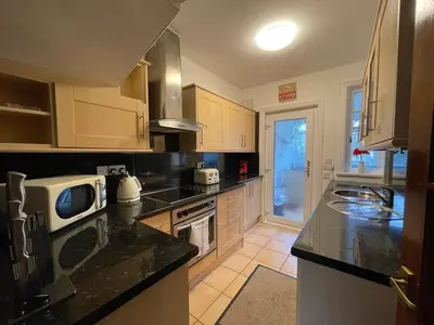 a kitchen with wooden cabinets and a counter top at 1930s 3Bed House in Quiet Village w/ Large Garden in Bishopton