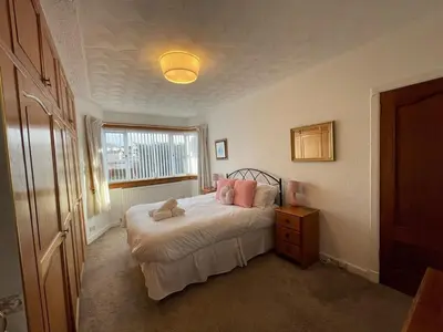 a bedroom with a bed with pink pillows and a window at 1930s 3Bed House in Quiet Village w/ Large Garden in Bishopton