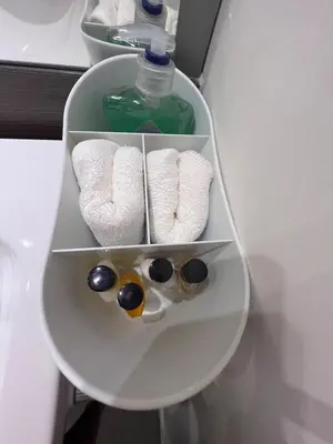 a shelf with three towels and a bottle of soap at Modern 2 Bedroom Flat in Quiet Village w/ Ensuite in Bishopton