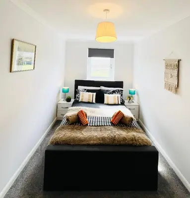 a bedroom with a black bed with pillows at Luxurious & Modern Apartment in Hawkhead