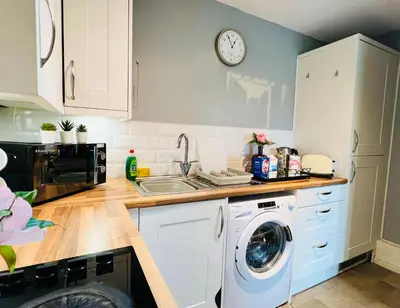 a kitchen with a washing machine and a clock on the wall at Luxurious & Modern Apartment in Hawkhead