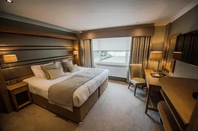 a hotel room with a bed and a desk and a window at Bowfield Hotel and Spa in Howwood