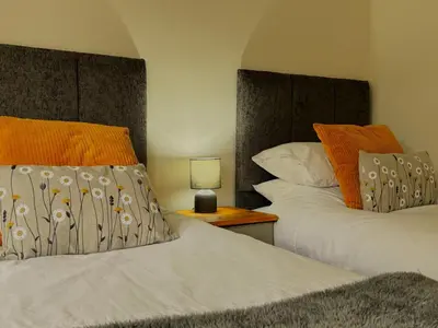 a bedroom with two beds and a lamp on a night stand at The Gate Lodge in Helensburgh