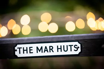 a sign that reads the marir huts with lights in the background at The Mar Huts - The Conic Hut in Drymen