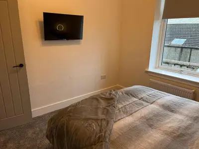 a bedroom with a bed and a flat screen tv on the wall at Barassie, Troon in Troon