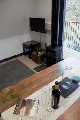 a living room with a table with wine glasses and a stove at Tigh Na Beithe in North Ballachulish