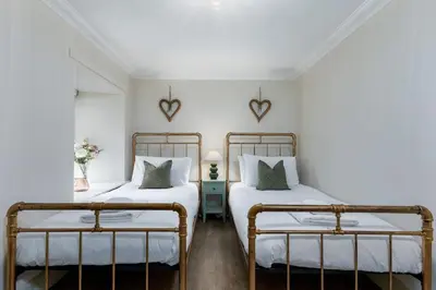 two beds in a room with white walls at The Tranquil Auchterarder 3-bed Cottage in Auchterarder