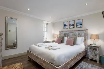 a bedroom with a large white bed with a mirror at The Tranquil Auchterarder 3-bed Cottage in Auchterarder