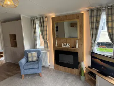 a living room with a fireplace and a chair and a tv at Campsie Glen Holiday Park in Glasgow