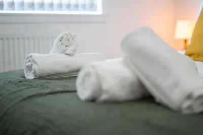 a bed with towels and a remote control on it at 2 Bedroom Apartment-Free Parking-by Holiday Homes in Wishaw