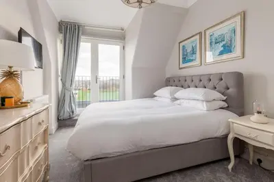 a white bedroom with a large bed and a window at Beautiful Victorian Apartment close to the Botanical gardens, Free parking! in Edinburgh