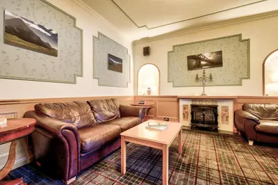 a living room with leather furniture and a fireplace at Onich Hotel & Lochside Beach Pods in Onich