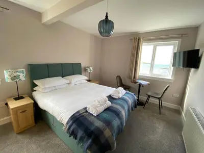 a bedroom with a bed and a desk and a window at Bunessan Inn in Bunessan