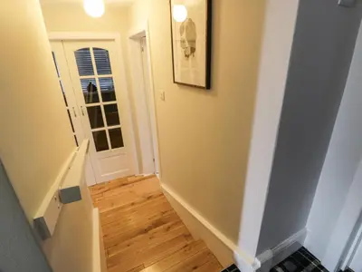 a hallway with a staircase with a door and wooden floors at Lower Neuk in Dunfermline
