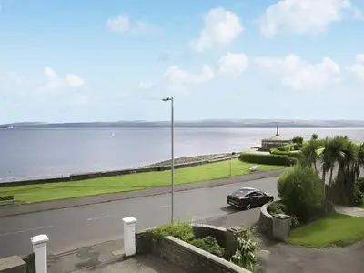 a car parked on a road next to a body of water at Island Seaview Villa in Rothesay
